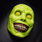 Adult masked monster latex horror mask in bright green with yellow bulging eyes and exposed teeth