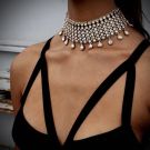 Gold crystal choker necklace with wide collar design and teardrop pendants on black background