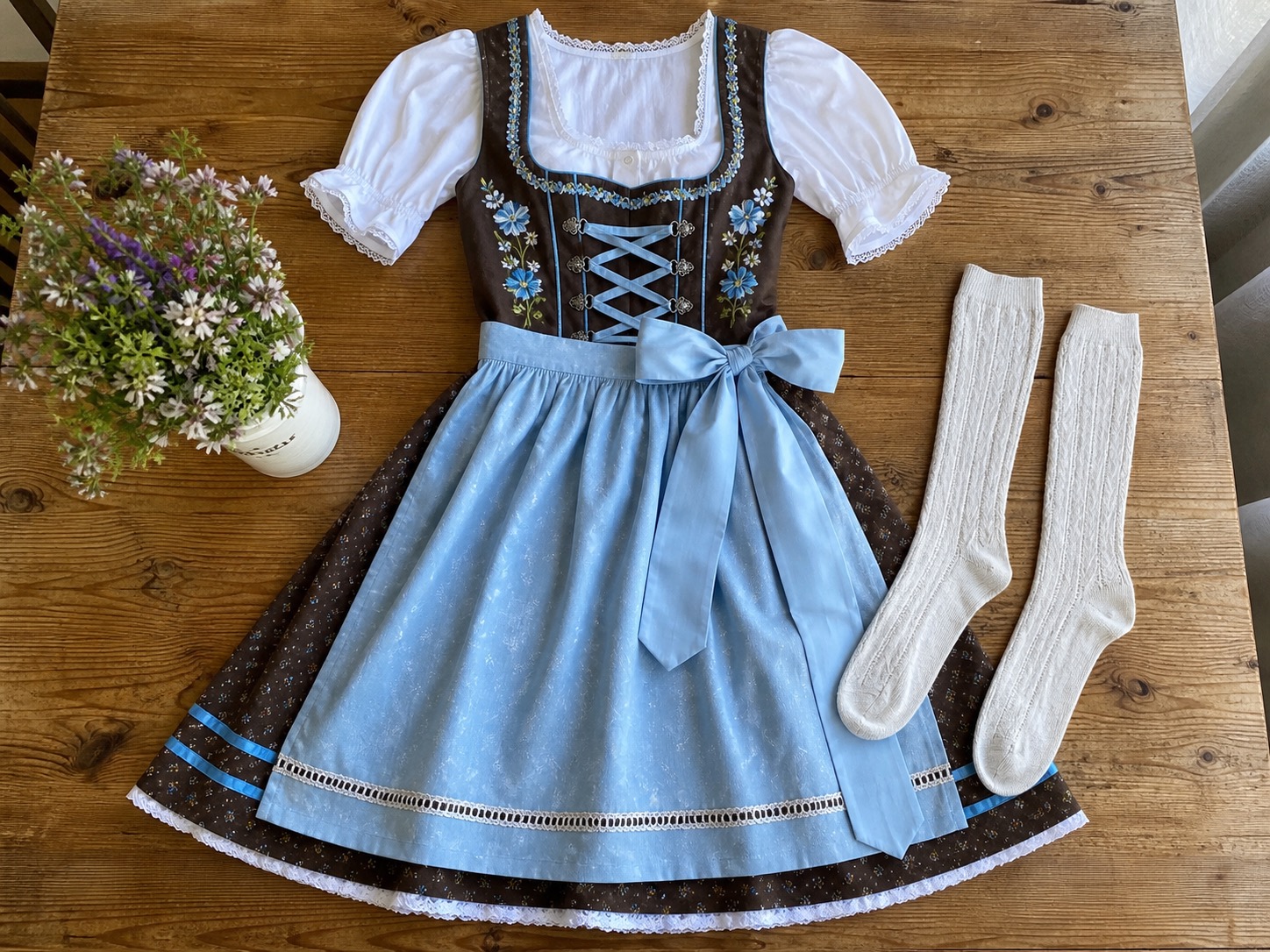 A complete dirndl costume set arranged with an apron bow and knee-high socks