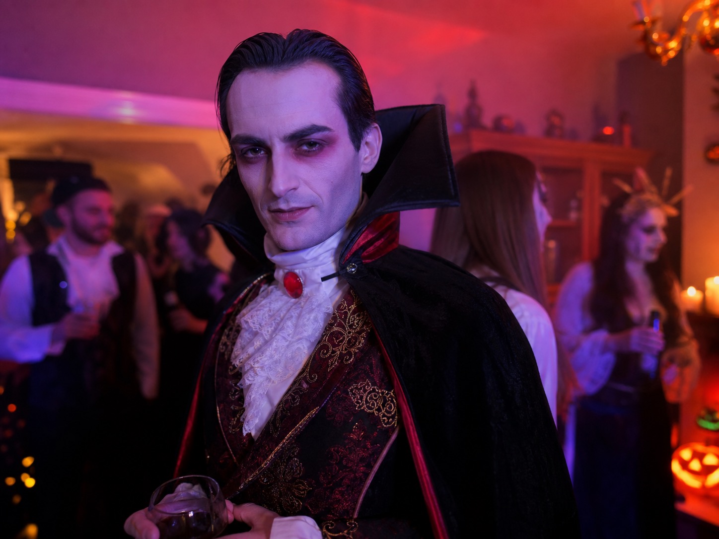 A man wearing a full vampire-style Halloween costume at an indoor party